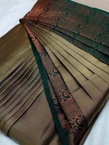 A unique bronze-colored saree with a green border. The pleats are done to enhance the metallic sheen of the fabric.