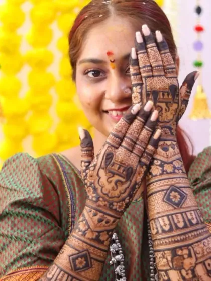 A close-up of the bride's hands, showcasing the detailed elephant and kalash motifs on her palms.