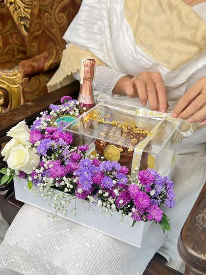 Unboxing the experience. This hamper is being prepared for a celebration, showcasing the clear acrylic box that protects and displays the beautiful arrangement inside.