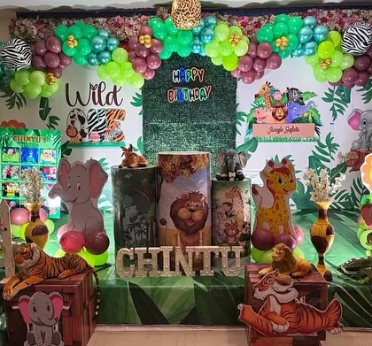 A vibrant and immersive jungle safari themed birthday party. This grand setup features a full-stage backdrop with animal cutouts, a massive balloon arch in jungle colors, and themed props to create a wild adventure.