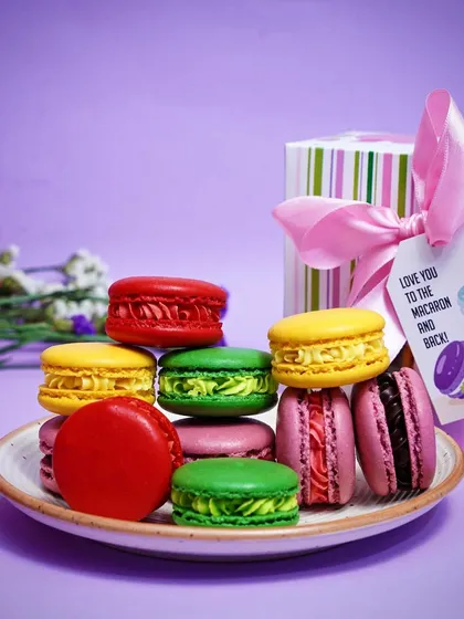 A side-angle view of stacked macarons on a plate, showing their texture and filling. This detailed shot emphasizes the quality and craftsmanship of the baked goods.