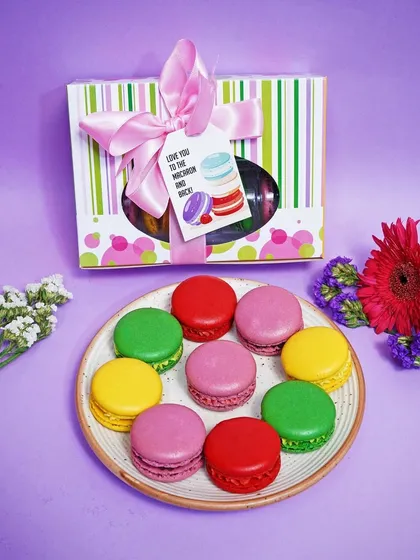 A neat arrangement of colorful macarons on a plate, with the gift box placed behind. This clean, top-down shot is excellent for e-commerce listings and product catalogs.