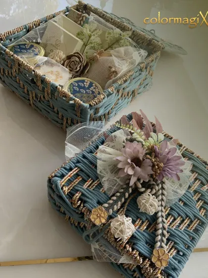 This elegant blue woven box is a sophisticated Rakhi gift. It opens to reveal a curated selection of treats, all adorned with delicate floral and lace details.