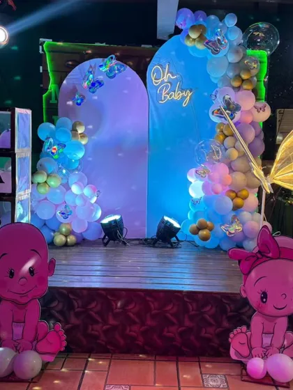 A stylish 'Oh Baby' stage setup with modern arched backdrops in shades of blue. The decor is enhanced with a neon sign, butterfly accents, and character cutouts.