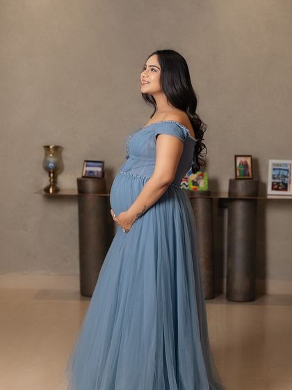 A vision in blue. This elegant studio portrait features the mother-to-be in a beautiful, flowing blue gown, her expression serene and hopeful.