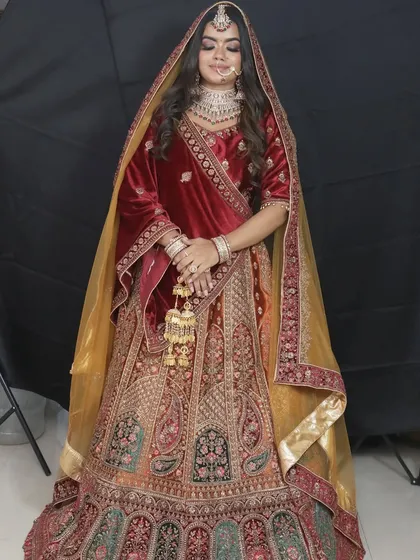 This maroon velvet lehenga is a favorite for winter weddings. The gold embroidery and matching kalire give it a truly royal feel.