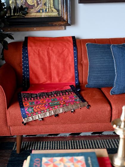 The silk runner displayed on a sofa, adding a splash of color and global style. Each runner is custom-made, allowing us to play with different textile combinations.