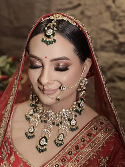 A close-up of this bride's stunning eye makeup. I created a bronze and gold glittery look with a sharp wing, which beautifully complements her traditional red attire and emerald jewelry.