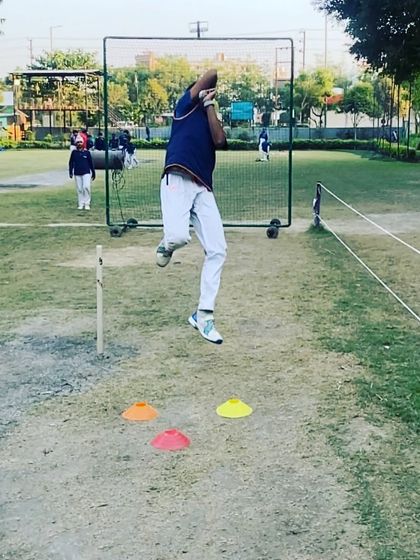 The jump is a critical part of the bowling action. Here, a player is in mid-air, demonstrating the explosive energy we train our bowlers to generate.