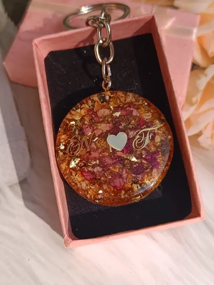 This round keychain was made from a client's flowers and personalized with the initials 'N' and 'F'. It's a lovely way for a couple to share a memory.