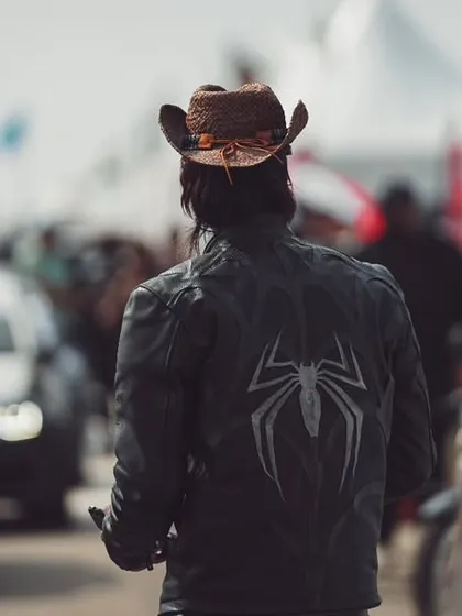 A lone wanderer walks through the paddock, a sea of performance cars on one side and vendor tents on the other. This image captures the scale and atmosphere of the Vroom festival grounds.