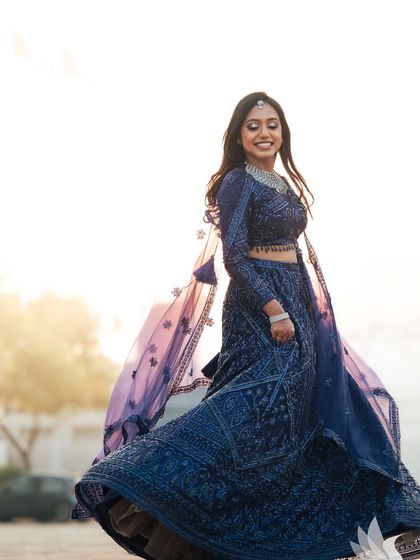 A joyful, twirling shot of Dr. Akshara in her magnificent reception lehenga. The outdoor lighting captures the sparkle of her outfit and the radiance of her glam makeup look.