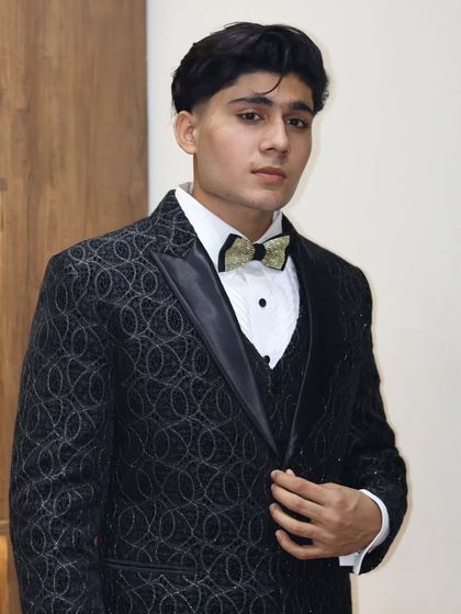 A front view of the black patterned tuxedo, highlighting the detailed fabric and the elegant satin lapels. This is a perfect choice for a groom or for any formal celebration.