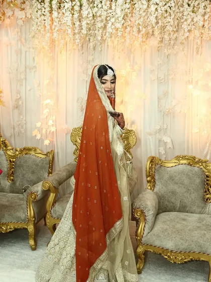 A full-length shot showing her unique white and gold lehenga with a contrasting orange dupatta.