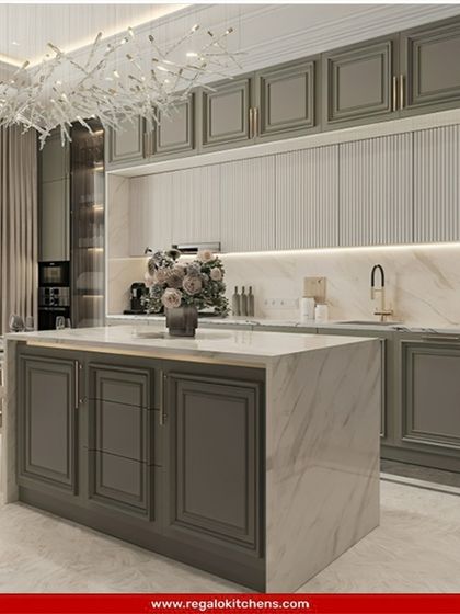 Classic elegance redefined. This kitchen features traditional raised-panel cabinets in a sophisticated grey, a marble island, and a stunning modern chandelier. It’s a perfect example of how we blend timeless design with contemporary luxury.