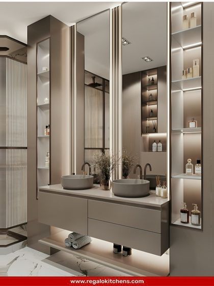 A sophisticated double vanity with grey vessel sinks and tall, illuminated storage cabinets. The metallic finish and sleek lines give this bathroom a high-end, hotel-like feel.