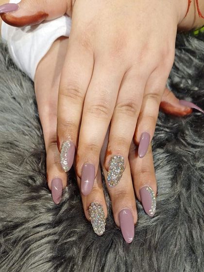 A statement look combining dusty rose polish with accent nails fully covered in chunky silver glitter and crystals.