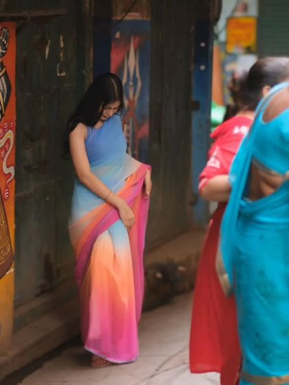 The vibrant colors of a saree against the timeless art of Varanasi's streets. This candid shot captures the life and energy of the city's narrow lanes.