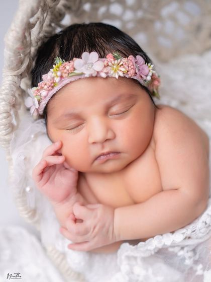 A close-up of a beautiful sleeping newborn wearing a floral headband.