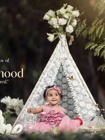The joy of childhood captured. A little girl in a pink dress sits in her teepee, surrounded by the beauty of the park.