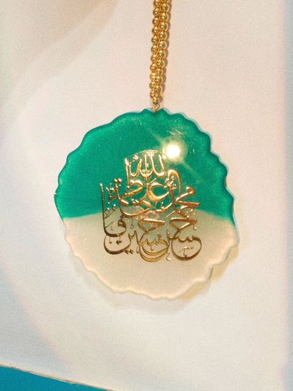 This version of the Panjatan car hanging uses a two-tone design with teal and white resin. The gold calligraphy stands out beautifully against both colors.