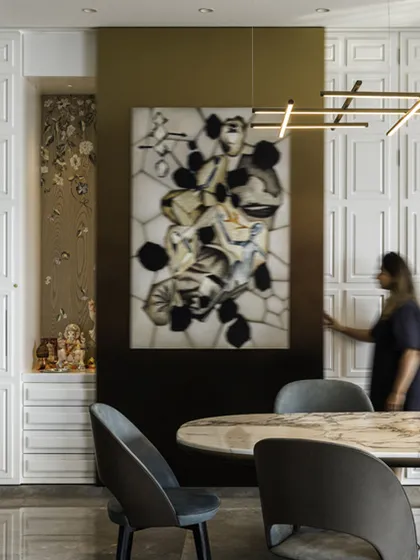 A hidden puja space is artfully concealed behind paneled doors next to the dining area in this modern fusion home. The design seamlessly integrates family traditions with contemporary aesthetics, using a neutral palette and warm lighting to create a serene atmosphere.