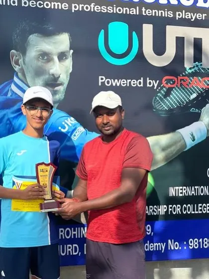 Khushank Bhushan celebrates his first UTR tournament title win in Delhi. He is seen here receiving his plaque from his coach in front of the UTR banner.