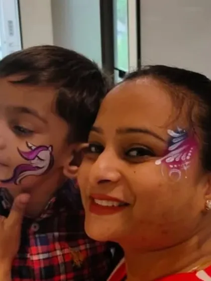 A mother and son duo with matching face paint themes, a unicorn for him and an abstract design for her.
