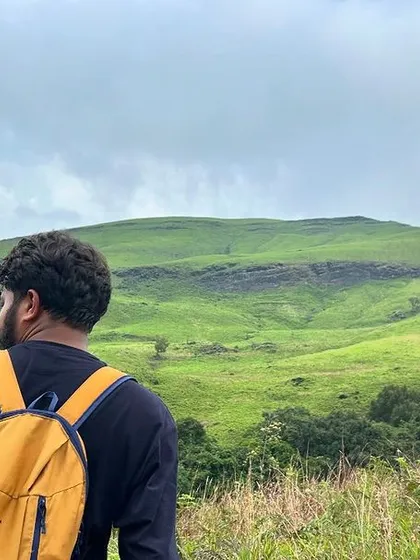 A trekker looking out at the vast green expanse of Kudremukh National Park.