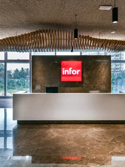 The reception for Infor, featuring a minimalist desk against a marble wall. The standout feature is the parametrically designed wooden wave structure suspended from the ceiling, adding a sense of movement and artistry.