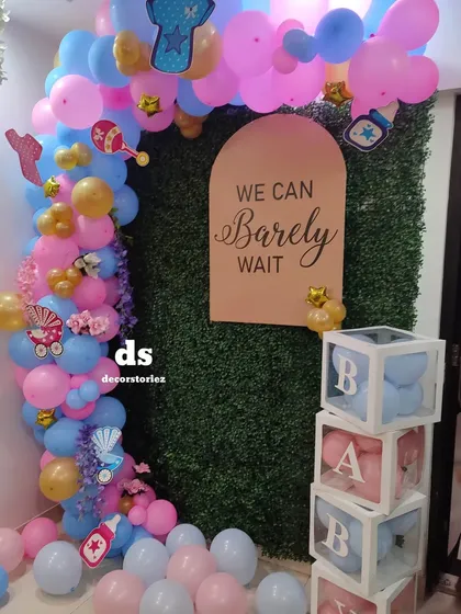 Here is a popular baby shower theme we created, perfect for a gender reveal or welcoming a new arrival. The setup includes a pink and blue balloon arch against a green wall, a custom "We Can Barely Wait" sign, and transparent 'BABY' blocks filled with matching balloons.