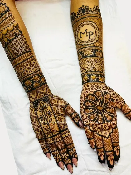 This design was personalized with the couple's initials 'MP' in a lovely monogram. It's paired with a large mandala on the other hand and bands of lotus and geometric patterns.