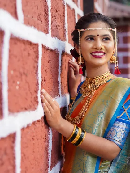 A Maharashtrian bride in all her glory. I focused on capturing her serene expression and the intricate details of her bridal look, from the traditional 'mundavalya' to the rich texture of her Paithani saree, against a rustic brick wall.
