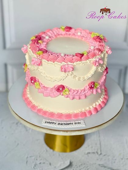 A classic vintage cake with intricate pink piping, ruffles, and floral details for a timeless and romantic look.