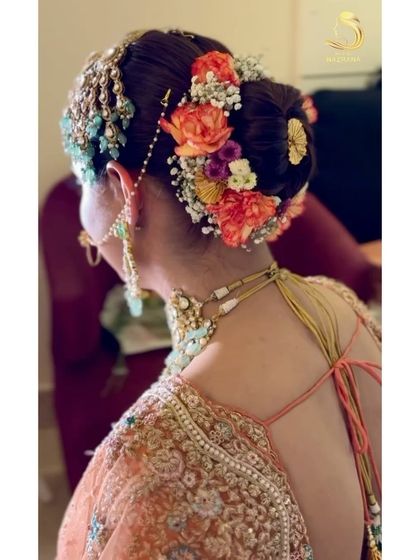 A side view of a gorgeous bridal bun with a mix of orange and white flowers, perfectly complementing the bride's passa.