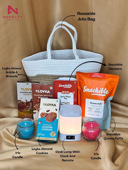 A beautiful blend of treats and tech in a reusable jute and cotton basket. This hamper contains a desk lamp with a clock, iris candles, and a variety of snacks like almond brittle, cookies, and quinoa puffs.
