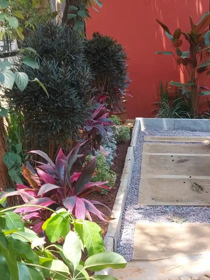 A multi-level garden path using concrete steps and a gravel border. The planting includes colorful Cordyline and other foliage plants to soften the hardscape elements.