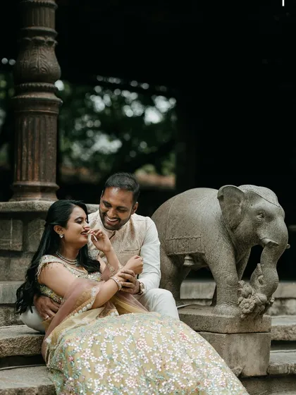 An intimate moment on the stone steps, with the groom whispering to his bride, next to a classic elephant statue.