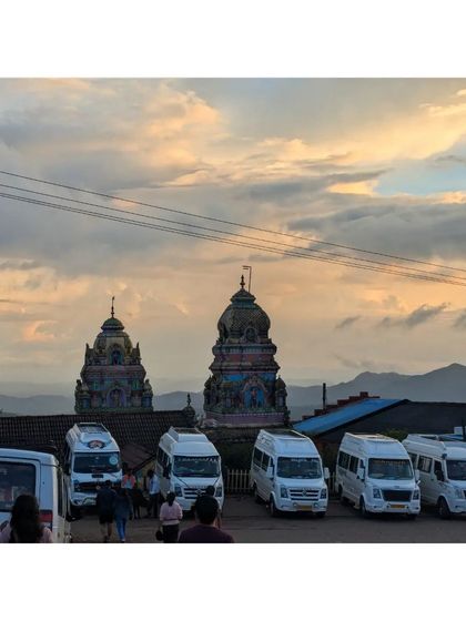 Our fleet of traveller vans parked near a temple at sunset in Chikmagalur. We handle all the logistics so you can just enjoy the journey.
