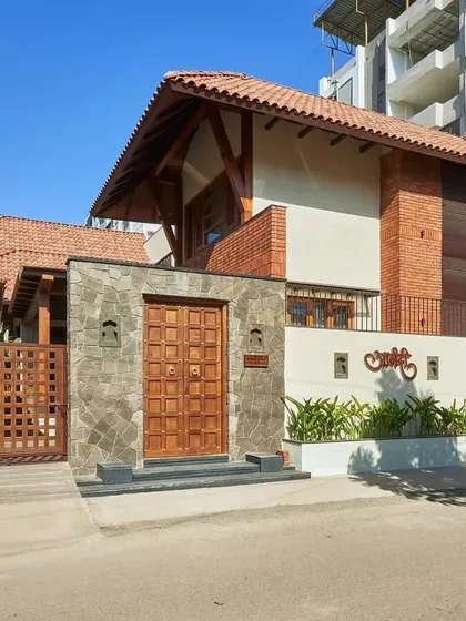 The street view of the 'Anandi' house, showcasing its unique blend of tropical contemporary style with traditional materials like brick and stone.