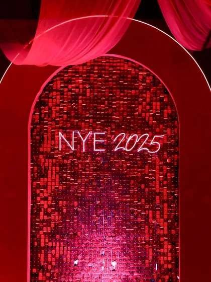 A close-up of our custom photo backdrop, featuring a shimmering red sequin wall and a neon 'NYE 2025' sign, framed by a classic archway. It was a popular spot for guests all night.