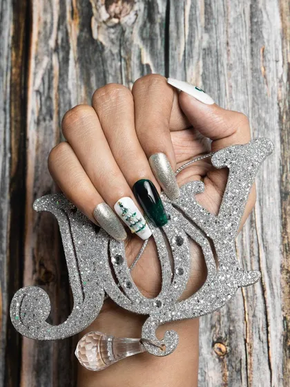 This Christmas-themed set combines silver glitter, deep green chrome, and a white nail with a hand-painted Christmas tree. It's a perfect example of a mixed-finish holiday manicure.