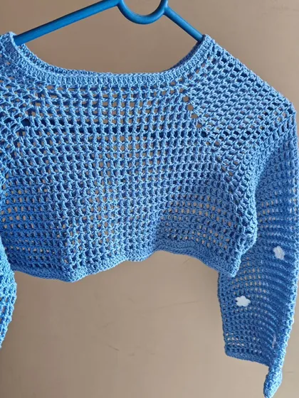Another angle of the light blue shrug, highlighting the bell sleeves and the placement of the daisy details.