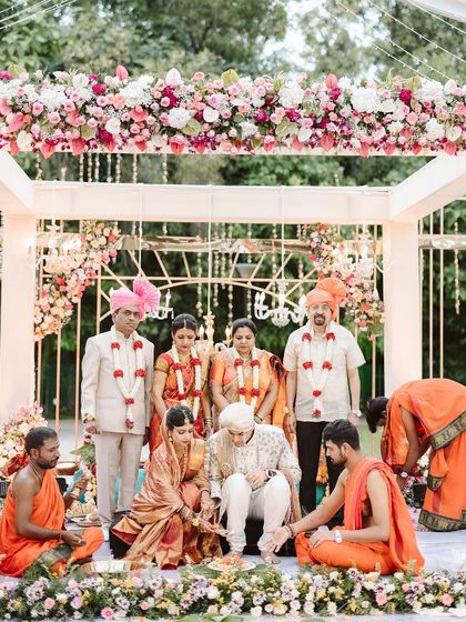 A beautiful moment from the wedding ceremony, with the family gathered under the elegant floral mandap. The overhead arrangement of pink and white roses created a soft and romantic canopy for the rituals.