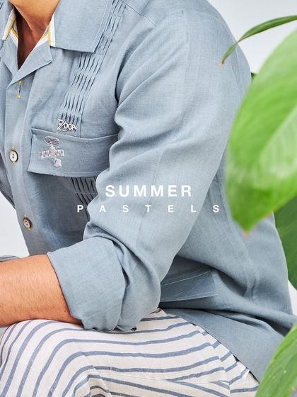 Summer pastels that are poised and just so perfect. This image showcases a light blue utility shirt paired with striped trousers for a relaxed, stylish look.