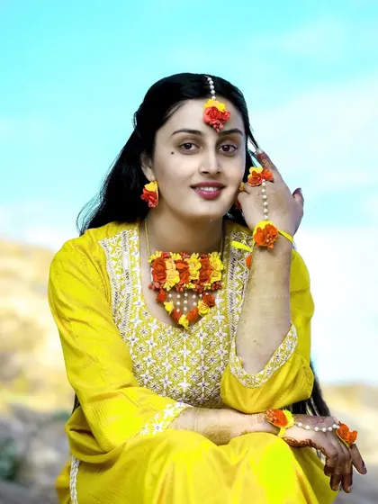 A lovely seated portrait of the bride-to-be, looking radiant in her yellow outfit and floral accessories.