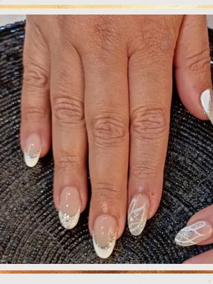 A beautiful bridal or party look. This set features a classic white French tip with some nails accented by a silver glitter ombré and delicate white line art.
