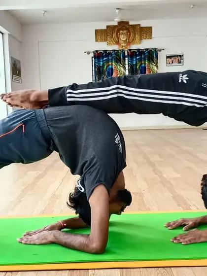 A beautiful partner backbend where one student supports the other in a forearm wheel pose. This allows for a deeper opening than one could achieve alone.