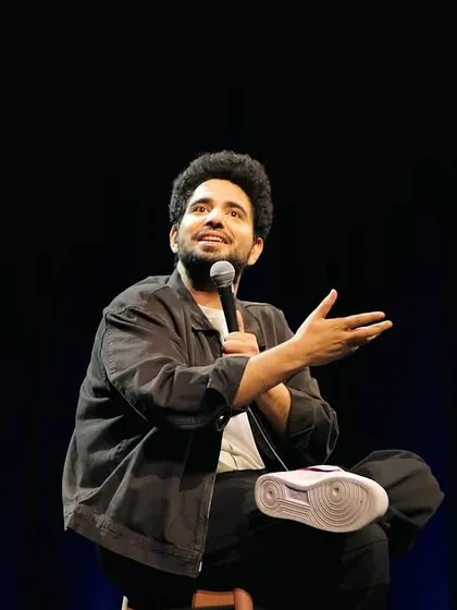 Comedian Samay Raina on stage during his standup special, with his custom "Unfiltered" Nike Air Force 1s prominently featured.