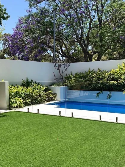 I can create a clean, modern look with a perfect poolside lawn. This backyard features a seamless transition from the crisp turf to the pool deck, surrounded by lush greenery that provides privacy without feeling closed in.